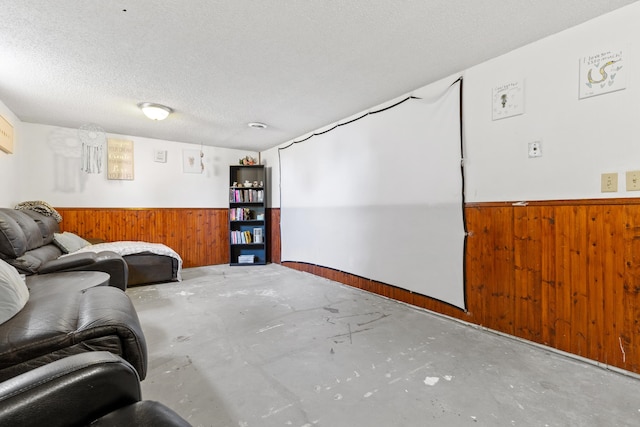 living room featuring a textured ceiling, wooden walls, and concrete flooring