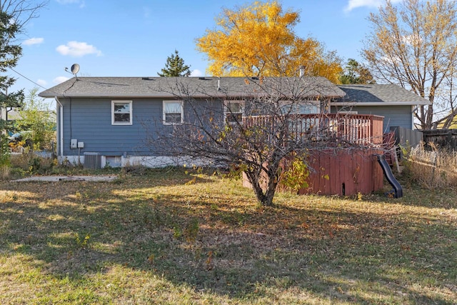 rear view of house featuring a wooden deck and a lawn