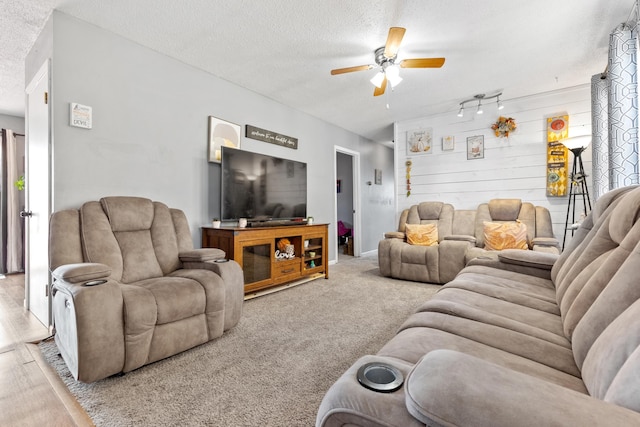 living room featuring a textured ceiling, wooden walls, carpet flooring, and ceiling fan