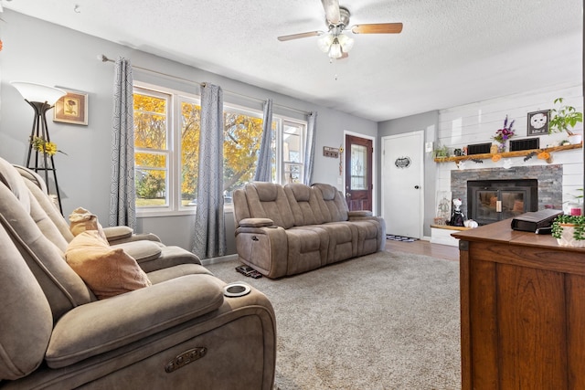 living room featuring a fireplace, a textured ceiling, carpet, and ceiling fan