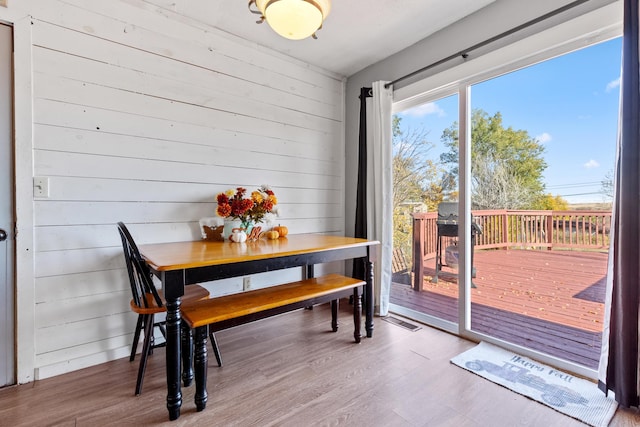 dining space with wood-type flooring and wood walls