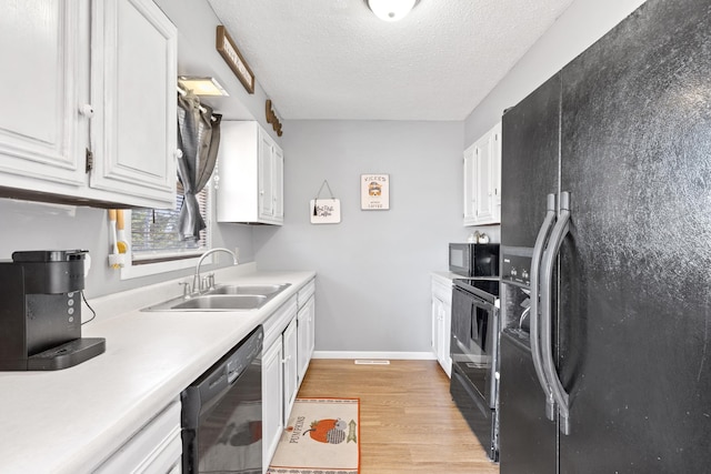 kitchen with sink, black appliances, light wood-type flooring, white cabinets, and a textured ceiling