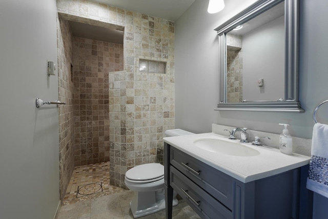 bathroom featuring vanity, toilet, tile patterned floors, and a tile shower