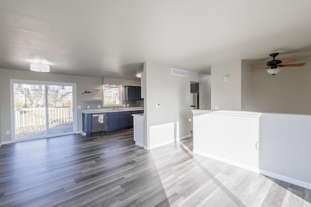 unfurnished living room featuring sink, wood-type flooring, and ceiling fan