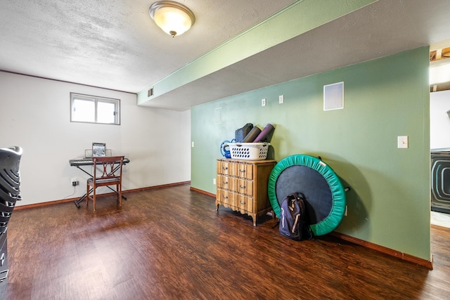 misc room with dark wood-type flooring and a textured ceiling