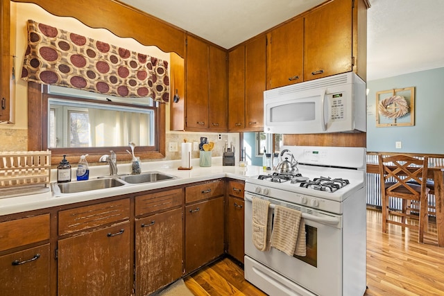 kitchen featuring white appliances, tasteful backsplash, sink, and light wood-type flooring