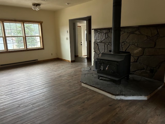 living room with dark wood-type flooring, a wood stove, and a baseboard heating unit