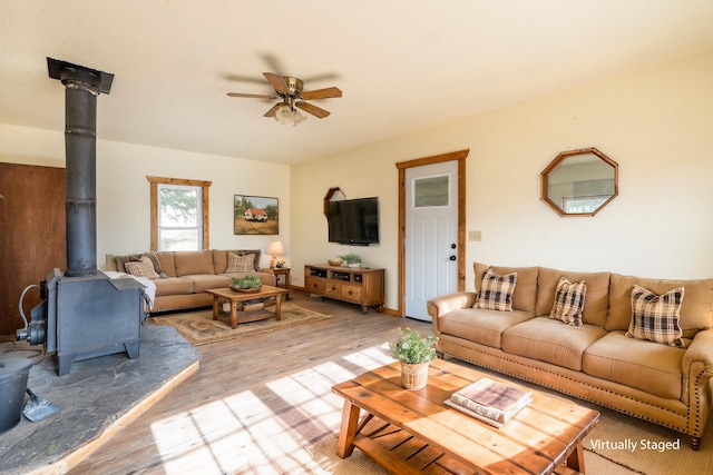 living room featuring ceiling fan, a wood stove, and hardwood / wood-style floors