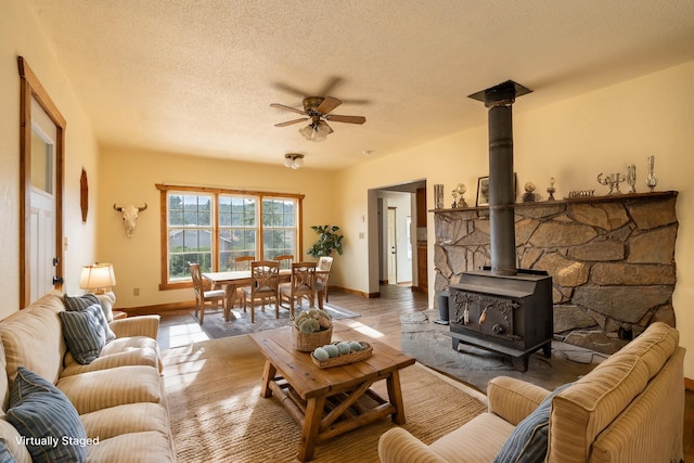 living room with a textured ceiling, a wood stove, and ceiling fan