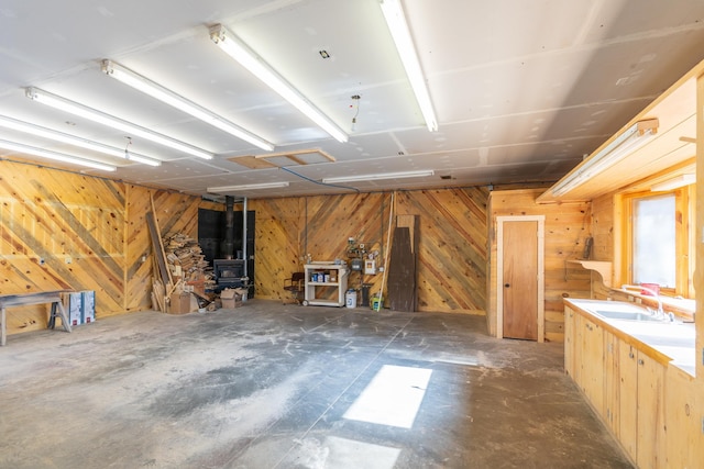 garage featuring wood walls, a wood stove, and sink