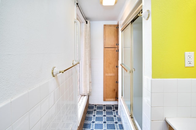 bathroom with a shower with door and tile walls