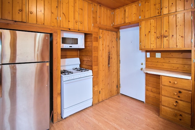 kitchen featuring white appliances, light wood-type flooring, wooden ceiling, and wooden walls