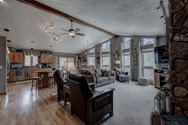 living room featuring beam ceiling, a healthy amount of sunlight, light wood-type flooring, and ceiling fan