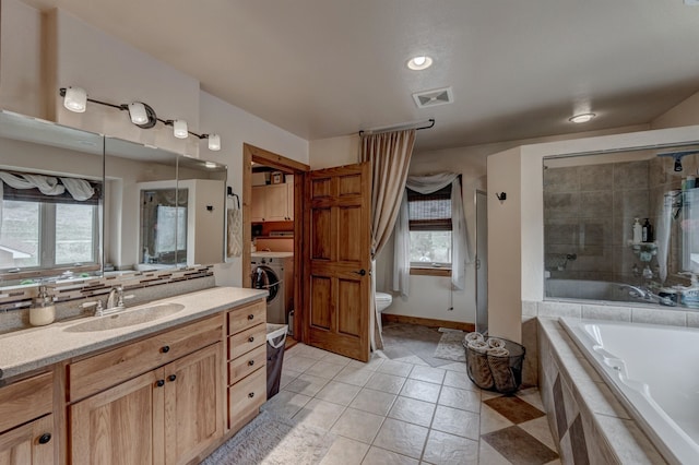 full bathroom with washer / clothes dryer, separate shower and tub, toilet, tile patterned floors, and vanity