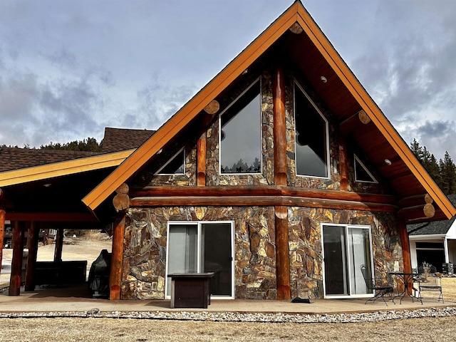 115 Minor Lake Cir, Hill City, SD 57745 - rear view of house with a patio area, a shingled roof, stone siding, and a lawn
