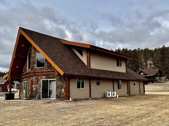 115 Minor Lake Cir, Hill City, SD 57745 - back of property with a patio area, roof with shingles, stone siding, and a yard