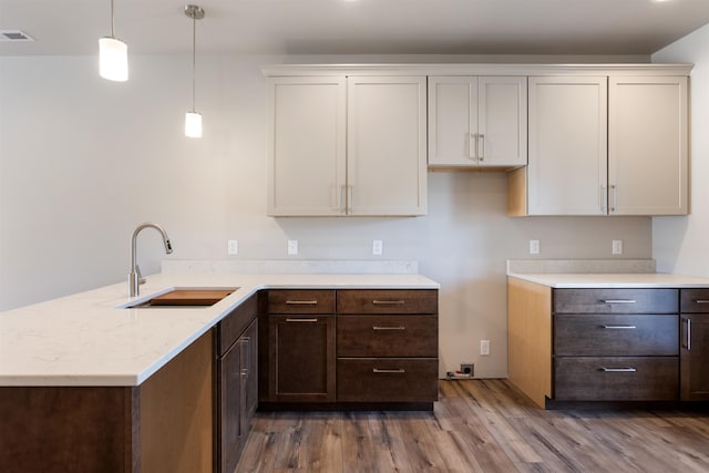 kitchen with white cabinetry, hardwood / wood-style floors, sink, and hanging light fixtures