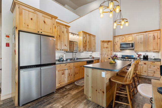 kitchen featuring hanging light fixtures, light brown cabinetry, dark wood-type flooring, a notable chandelier, and stainless steel appliances