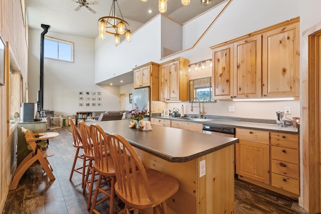 kitchen featuring sink, a wood stove, a high ceiling, and light brown cabinets