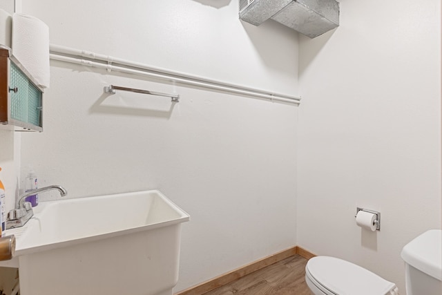 bathroom featuring toilet, sink, and wood-type flooring