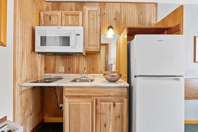 kitchen featuring sink, light brown cabinets, white appliances, and wood walls