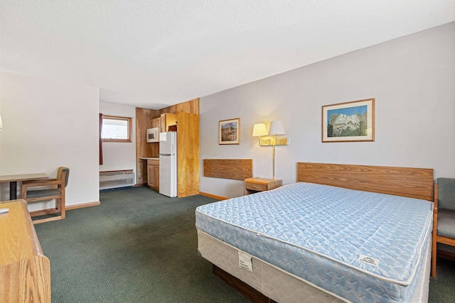 bedroom with baseboard heating, a textured ceiling, white refrigerator, and dark colored carpet