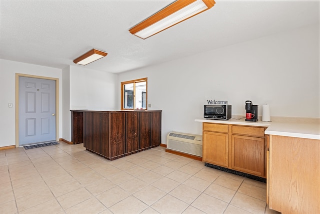 kitchen featuring an AC wall unit, kitchen peninsula, a textured ceiling, and light tile patterned floors