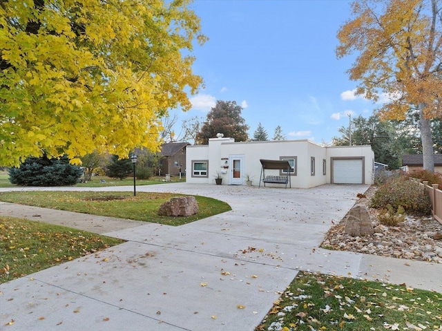 view of front of house featuring stucco siding, concrete driveway, an attached garage, and a front yard