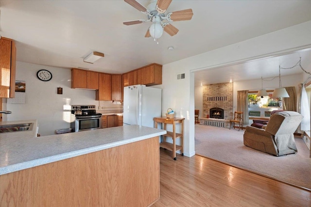 kitchen with stainless steel electric stove, freestanding refrigerator, a sink, a peninsula, and open floor plan