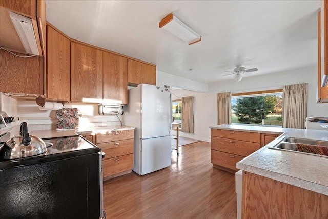 kitchen featuring electric stove, freestanding refrigerator, ceiling fan, light wood finished floors, and light countertops