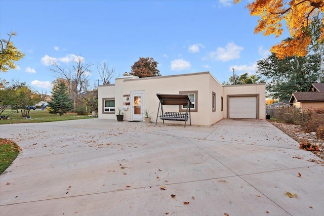 view of front of house with an attached garage, stucco siding, and concrete driveway