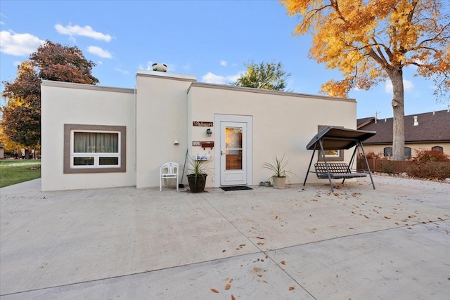 back of property with a patio and stucco siding