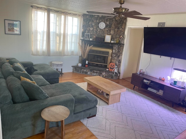 living room featuring hardwood / wood-style floors, a fireplace, a textured ceiling, and ceiling fan