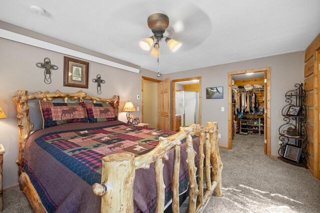 carpeted bedroom with a closet, ceiling fan, a walk in closet, and white fridge