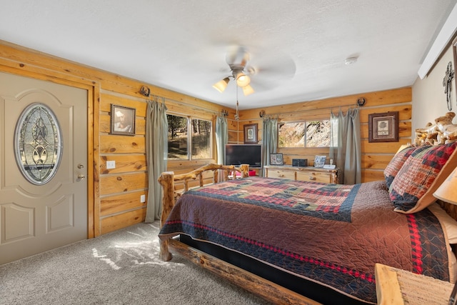 carpeted bedroom featuring wood walls, a textured ceiling, and ceiling fan