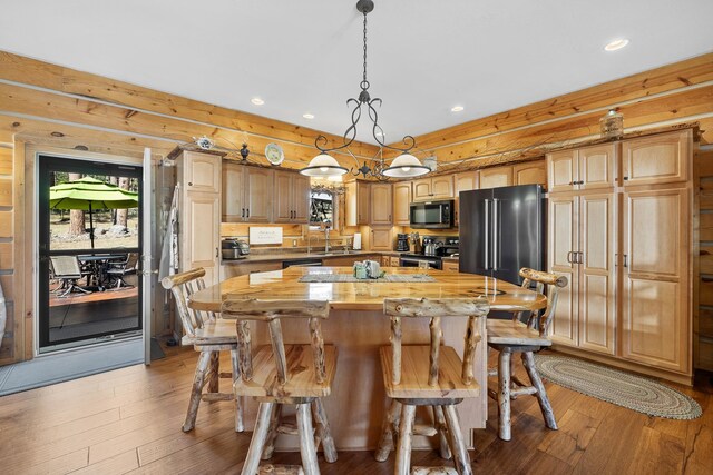 kitchen featuring a center island, appliances with stainless steel finishes, wood counters, hanging light fixtures, and light hardwood / wood-style flooring