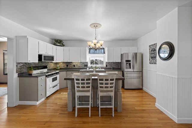 kitchen with light hardwood / wood-style floors, white cabinetry, appliances with stainless steel finishes, and a center island