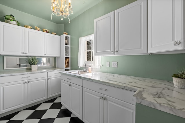 kitchen featuring white cabinetry, sink, decorative light fixtures, and a notable chandelier