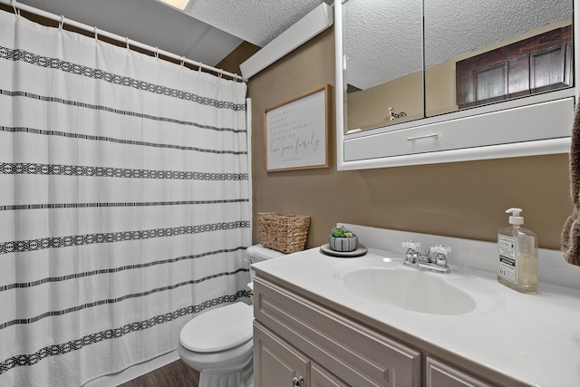 bathroom with toilet, hardwood / wood-style floors, vanity, and a textured ceiling