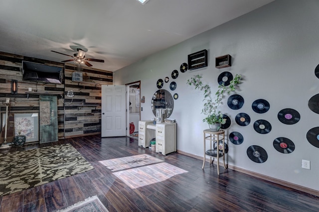 misc room with ceiling fan, wooden walls, and dark hardwood / wood-style floors