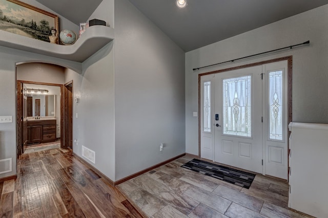 entryway with light hardwood / wood-style flooring, lofted ceiling, and sink