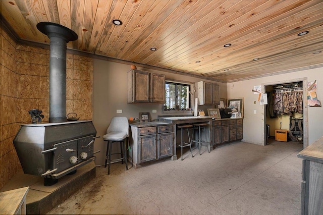 kitchen with wood ceiling, a wood stove, and dark brown cabinetry