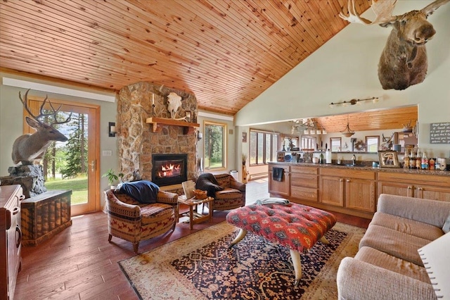 living room with a stone fireplace, high vaulted ceiling, sink, dark wood-type flooring, and wooden ceiling