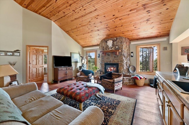 living room featuring a stone fireplace, wood ceiling, light hardwood / wood-style floors, and plenty of natural light