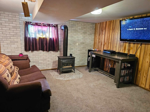 living room featuring a wood stove, wooden walls, light colored carpet, and brick wall