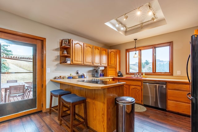 kitchen featuring dark hardwood / wood-style flooring, kitchen peninsula, black appliances, sink, and pendant lighting