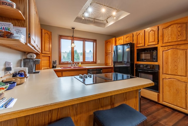 kitchen with kitchen peninsula, black appliances, sink, dark hardwood / wood-style floors, and pendant lighting