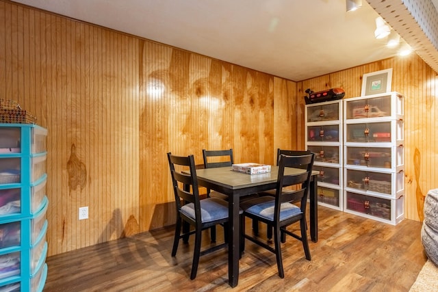 dining space with wood walls and wood-type flooring