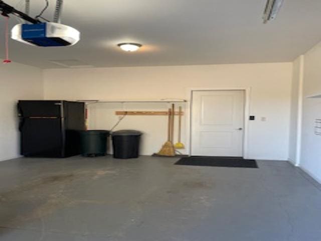 garage featuring a garage door opener and black fridge