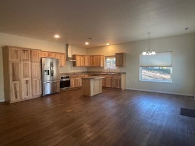 kitchen with dark hardwood / wood-style flooring, wall chimney range hood, a kitchen island, appliances with stainless steel finishes, and decorative light fixtures